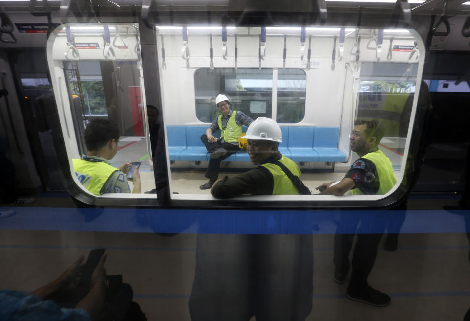 In this Feb. 21, 2019, photo, workers sit inside Mass Rapid Transit (MRT) during a trial run in Jakarta, Indonesia. Commuting in the gridlocked Indonesian capital will for some involve less frustration, sweat and fumes when its first subway line opens later this month. The 10-mile system running south from Jakarta's downtown is the first phase of a development that if fully realized will plant a cross-shaped network of stations in the teeming city of 30 million people. (AP Photo/Achmad Ibrahim)