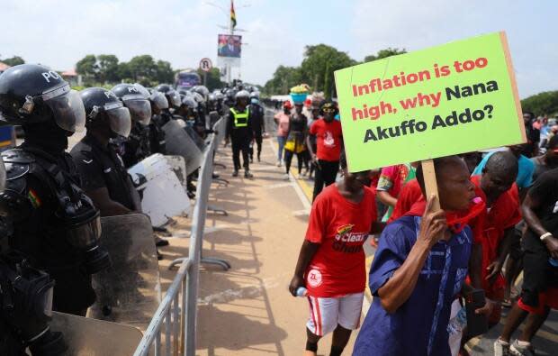 Police watch as protesters in Accra, Ghana, march toward the country's presidential palace in June 2022 as part of a demonstration protesting the soaring cost of living. 