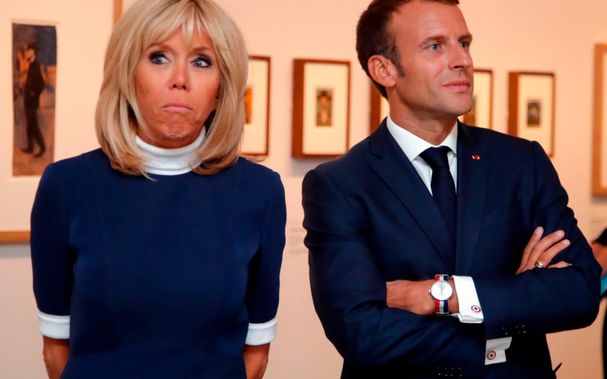 French President Emmanuel Macron (R) and his wife Brigitte Macron (C) visit the