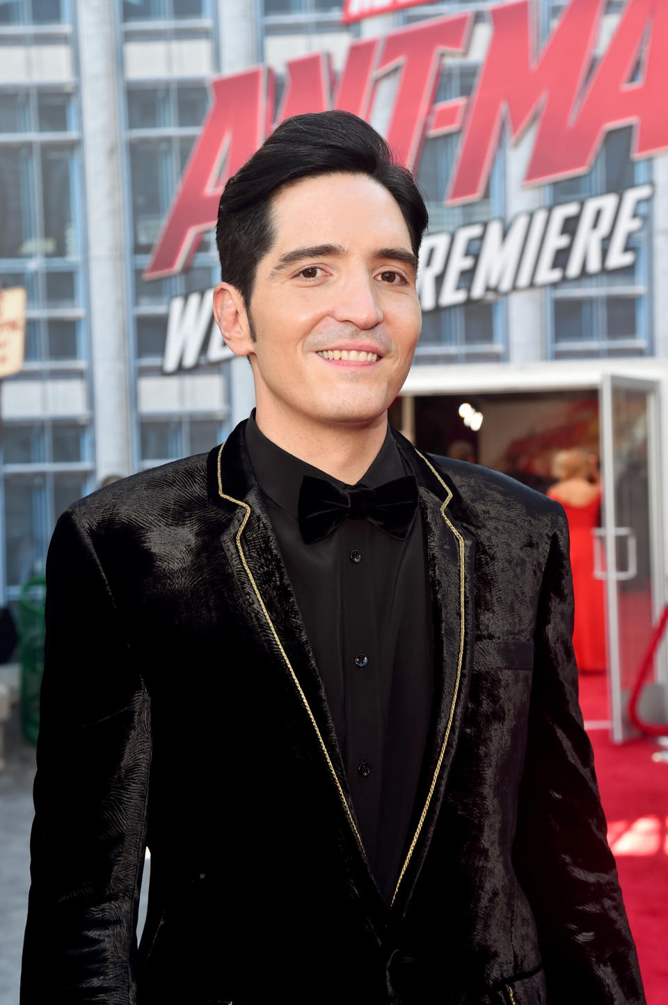 Head and shoulders shot of David smiling at the Ant-Man world premiere, wearing a black velvet jacket with gold trim around the lapels and a black shirt.
