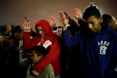 Members of a caravan of migrants from Central America, pray near the San Ysidro checkpoint after the first fellow migrants entered U.S. territory to seek asylum at improvised shelter in Tijuana, Mexico April 30, 2018. REUTERS/Edgard Garrido