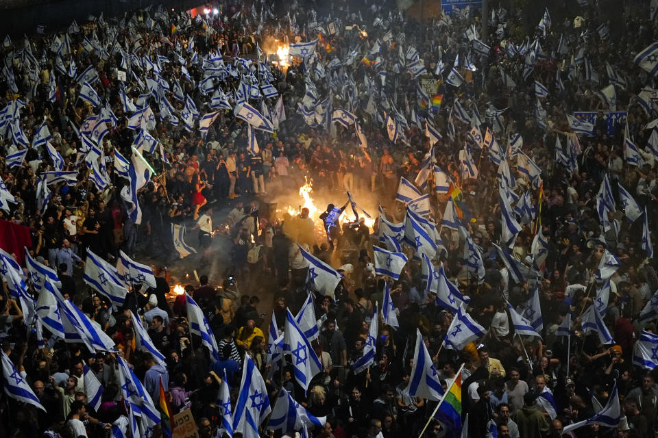 FILE - Israelis opposed to Prime Minister Benjamin Netanyahu's judicial overhaul plan set up bonfires and block a highway during a protest moments after the Israeli leader fired his defense minister, in Tel Aviv, Israel, Sunday, March 26, 2023. As Israel turns 75, it has much to celebrate. But instead of feting its accomplishments as a regional and economic powerhouse, the nation founded as a home for the world's Jews in the wake of the Holocaust finds itself under threat -- not by foreign enemies but by bitter internal divisions. (AP Photo/Ohad Zwigenberg, File)