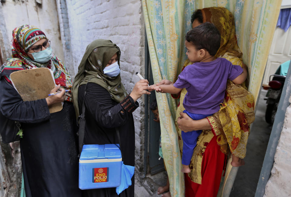 A health worker marks the finger of a child after administrating a polio vaccine in a neighborhood of Lahore, Pakistan, Monday, Aug. 2, 2021. The government launched polio vaccination drives across Pakistan in hopes to eradicate the crippling disease by the end of the year. (AP Photo/K.M. Chaudhry)