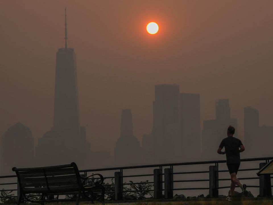 A man runs in front of the sun rising over the lower Manhattan skyline in Jersey City, N.J., June 8, 2023.