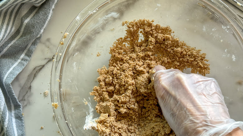 gloved hand mixing crumble