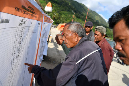 Villagers look at a list of missing passengers after a ferry sank last week in Lake Toba in Simalungun, North Sumatra, Indonesia, June 28, 2018. Picture taken June 28, 2018. Antara Foto/Sigid Kurniawan/via REUTERS