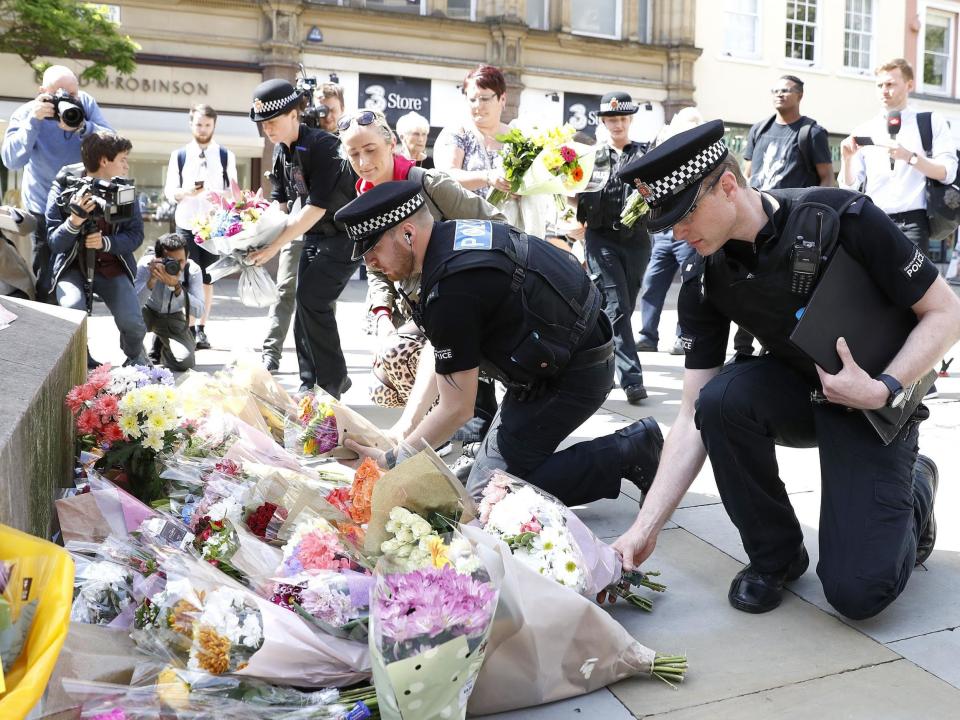 Police officers laying flowers in St Ann's Square, Manchester, the day after a suicide bomber killed 22 people, including children, as an explosion tore through fans leaving a pop concert in Manchester (PA)