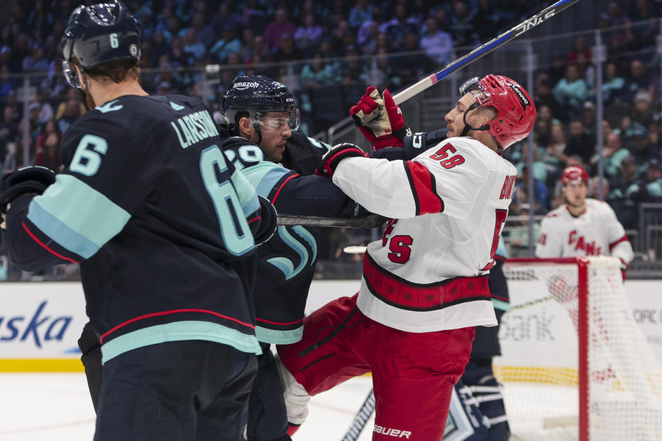 Seattle Kraken defenseman Vince Dunn, second from left, and Carolina Hurricanes left wing Michael Bunting (58) scuffle during the first period of an NHL hockey game Thursday, Oct. 19, 2023, in Seattle. (AP Photo/Jason Redmond)