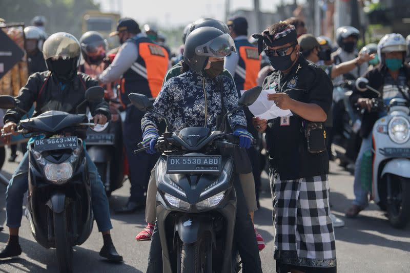 A staff member checks a rider’s documents during large-scale social restrictions to prevent the spread of coronavirus disease (COVID-19) in Denpasar