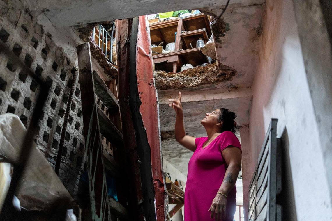 A woman points to damage in her roof, above the second story, caused by Hurricane Ian in Pinar del Rio, Cuba, Tuesday, Sept. 27, 2022.