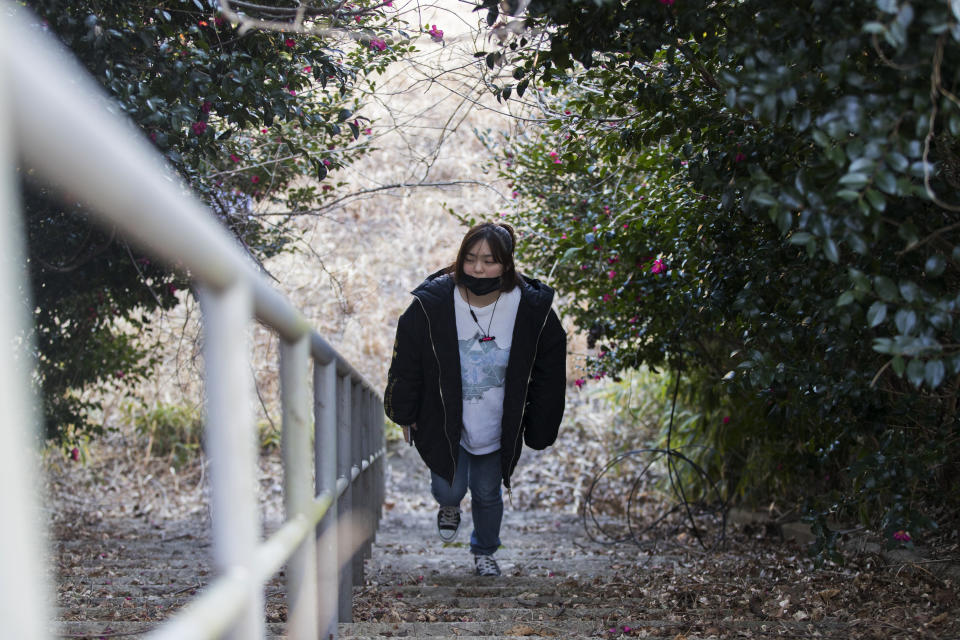 Hazuki Sato, a Futaba town official, walks around an elementary school she used to attend until she evacuated due to a nuclear scare following a 2011 earthquake, during an interview with The Associated Press in Futaba town, Fukushima prefecture, northeastern Japan, Sunday, Feb. 28, 2021. She's now preparing for the coming-of-age ceremony that is typical for Japanese 20-year-olds, hoping for a reunion in town so she can reconnect with her former classmates who have scattered. (AP Photo/Hiro Komae)