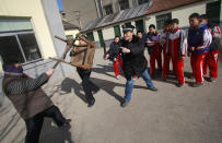Students stand behind as a policeman and a teacher try to defend them against an intruder during an anti-violence exercise at a primary school in Jinan, Shandong province, December 18, 2012. The exercise was held four days after last Friday's knife attack at a primary school in Henan province, leaving more than 20 children and an elderly villager injured. Picture taken December 18, 2012. REUTERS/China Daily (CHINA - Tags: CRIME LAW EDUCATION) CHINA OUT. NO COMMERCIAL OR EDITORIAL SALES IN CHINA