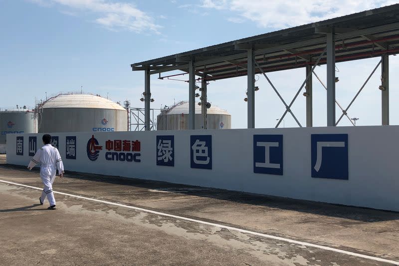 Worker walks past the logo of China National Offshore Oil Corporation (CNOOC) at its Nanshan liquefied natural gas (LNG) terminal in Hainan