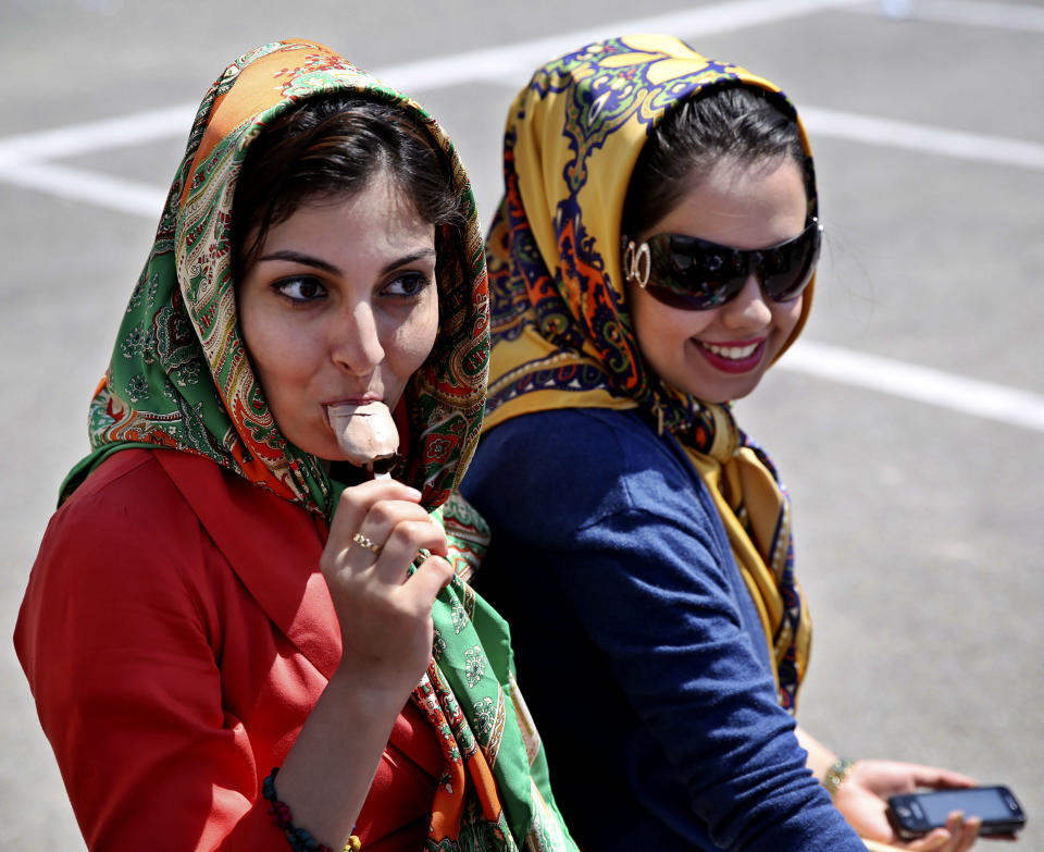 An Iranian woman eats ice-cream during a ceremony to unveil 5-tons of ice-cream at the Tochal mountainous area, of northern Tehran, Iran, Monday, April 1, 2013. Choopan dairy unveiled 5-tons of chocolate ice-cream, the largest in the world, according to the factory officials. (AP Photo/Ebrahim Noroozi)