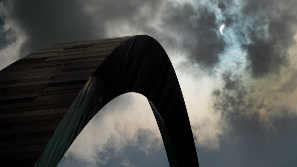 The moon partially blocks the sun in cloudy skies on August 21, 2017, over the Gateway Arch in St. Louis. - Jeff Roberson/AP