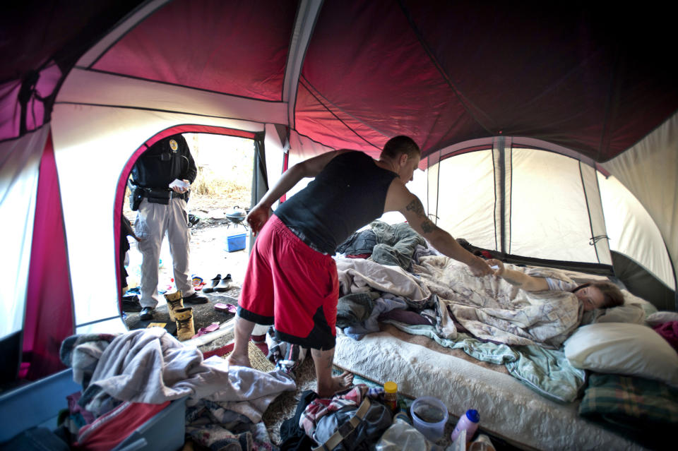 In this Tuesday, Jan. 21, 2014 photo, Homeless Liaison Officer Tom Gentner stands in the entrance to a tent as he searches for a suspected felon near the camps under the overpass of the Talmadge Memorial Bridge in Savannah, Ga. One of Gentner's homeless informants told him the new couple was bragging about skipping out on a $50,000 bond in Florida and being on the run from a felony charge of methamphetamine dealing. The were later arrested. (AP Photo/Stephen B. Morton)