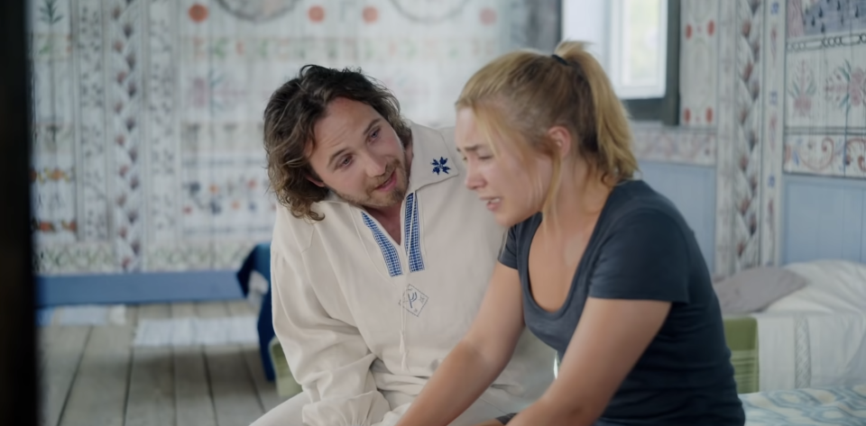 A man in Swedish traditional dress consoles a crying young woman