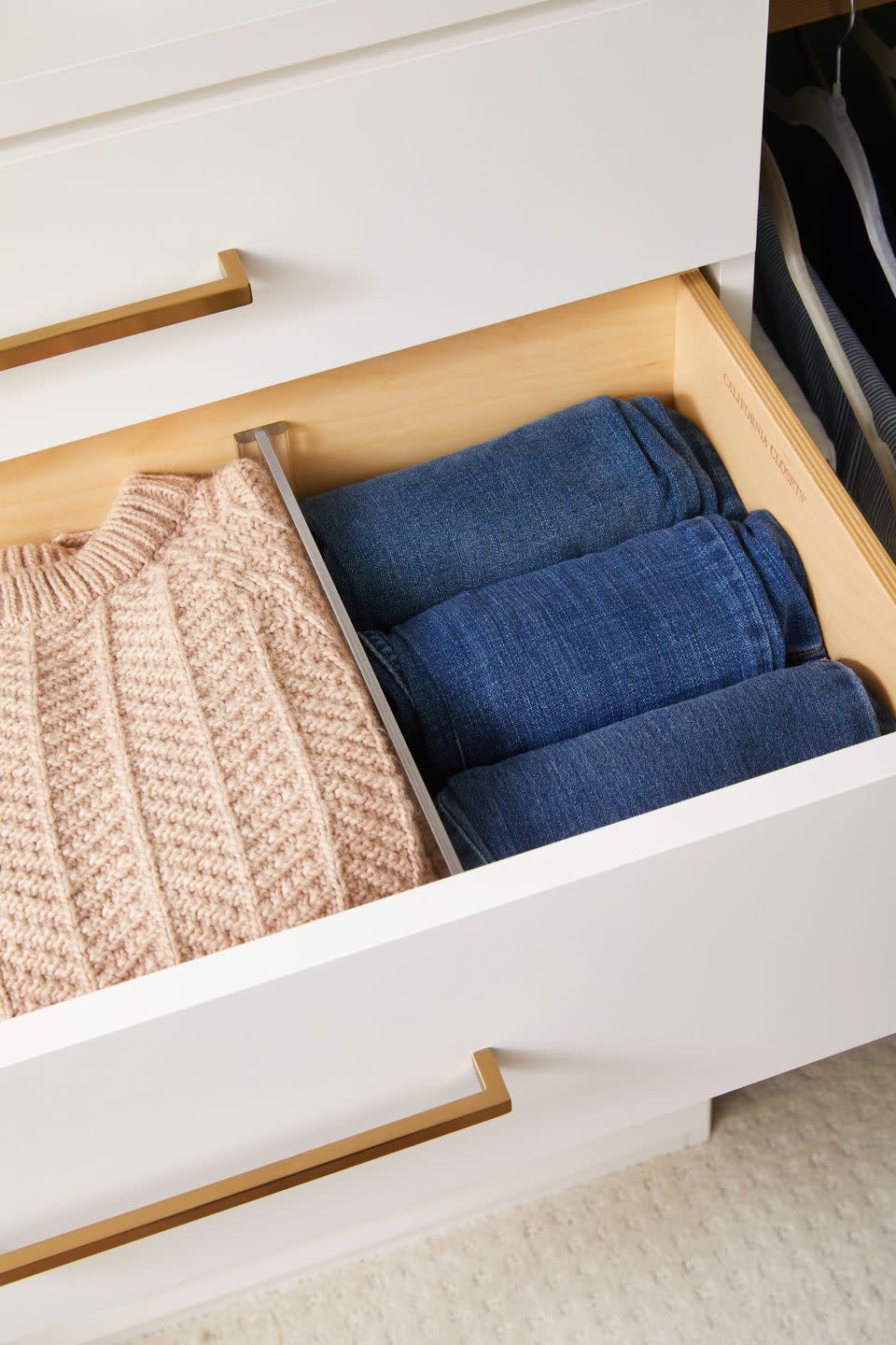 a drawer with sweaters and jeans inside