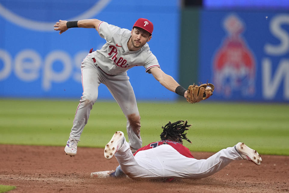 Cleveland Guardians' Jose Ramirez, bottom, advances to second base on a wild pitch by Philadelphia Phillies starting pitcher Ranger Suarez as shortstop Trea Turner, top, takes a throw in the fifth inning of a baseball game Friday, July 21, 2023, in Cleveland. (AP Photo/Sue Ogrocki)