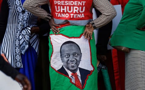 A supporter wears a cloth wrap showing Kenya's President Uhuru Kenyatta, with writing in Swahili reading "President Uhuru, Five More" referring to the wish for another 5-year term - Credit: AP