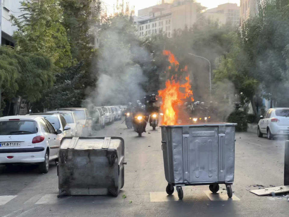 In this Tuesday, Sept. 20, 2022, photo taken by an individual not employed by the Associated Press and obtained by the AP outside Iran, a trash bin is burning as anti-riot police arrive during a protest over the death of a young woman who had been detained for violating the country's conservative dress code, in downtown Tehran, Iran. Iran faced international criticism on Tuesday over the death of a woman held by its morality police, which ignited three days of protests, including clashes with security forces in the capital and other unrest that claimed at least three lives. (AP Photo)