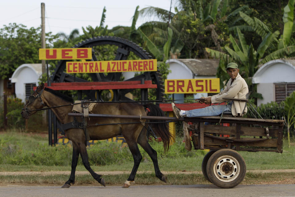 In this Sept. 8, 2012 photo, a man rides in a horse-drawn carriage outside the sugar processing plant "Brasil" in Jaronu, Cuba. Just two years ago, Cuba's sugar industry was on its knees after the worst harvest in more than a century. Now Cuba's signature industry is showing signs of life. Hulking processing plants are coming back online, and the harvest is growing by double digits each year, a boon to rural towns like Jaronu. (AP Photo/Franklin Reyes)