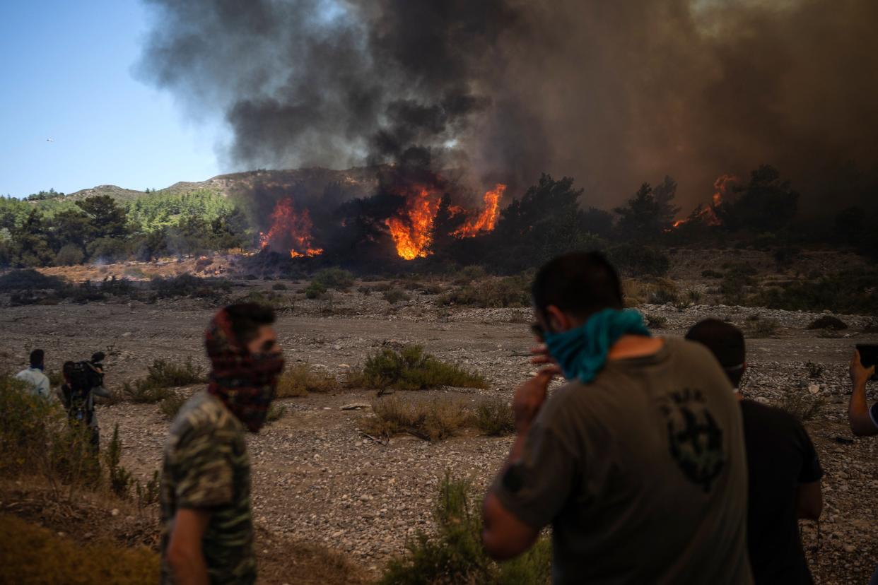 Locals watch the fires approaching the village of Vati, just north of the coastal town of Gennadi, in the southern part of the Greek island of Rhodes (AFP via Getty Images)