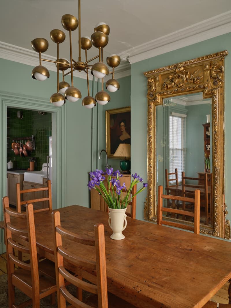 Brass multi-armed pendant light above wooden dining table in newly renovated home.