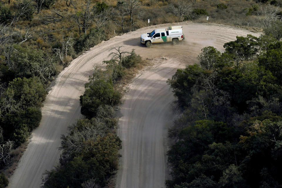 A Customs and Border Patrol vehicle carries two detained migrants down from Montezuma's Pass in Coronado National Memorial, Wednesday, Dec. 9, 2020, in Hereford, Ariz. Construction of the border wall, mostly in government owned wildlife refuges and Indigenous territory, has led to environmental damage and the scarring of unique desert and mountain landscapes that conservationists fear could be irreversible. (AP Photo/Matt York)