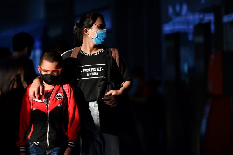A mother and her son, wearing protective face masks, are seen at a bus station after many workers crowded the terminal station to return to their cities after many activities have been closed due to coronavirus disease (COVID-19) outbreak in Bangkok