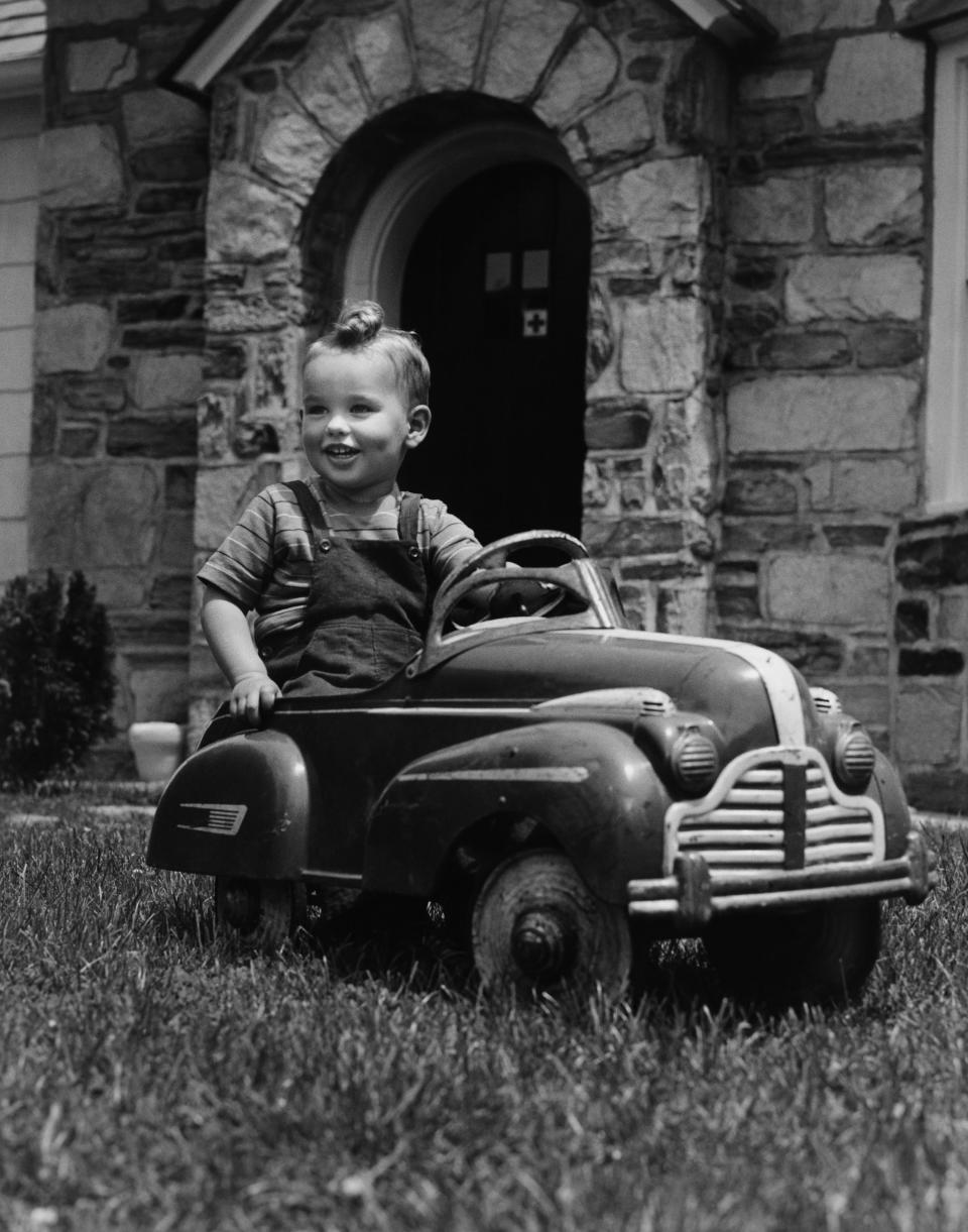 A little boy on an old pedal car