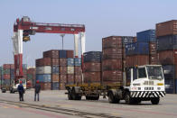 In this July 24, 2019, photo, workers watch as a truck passes by stacks of shipping containers at a port in Yingkou in northeastern China's Liaoning Province. Authorities in China's rust-belt region are looking for support for its revival from Beijing's multibillion-dollar initiative to build ports, railways and other projects abroad. (AP Photo/Olivia Zhang)