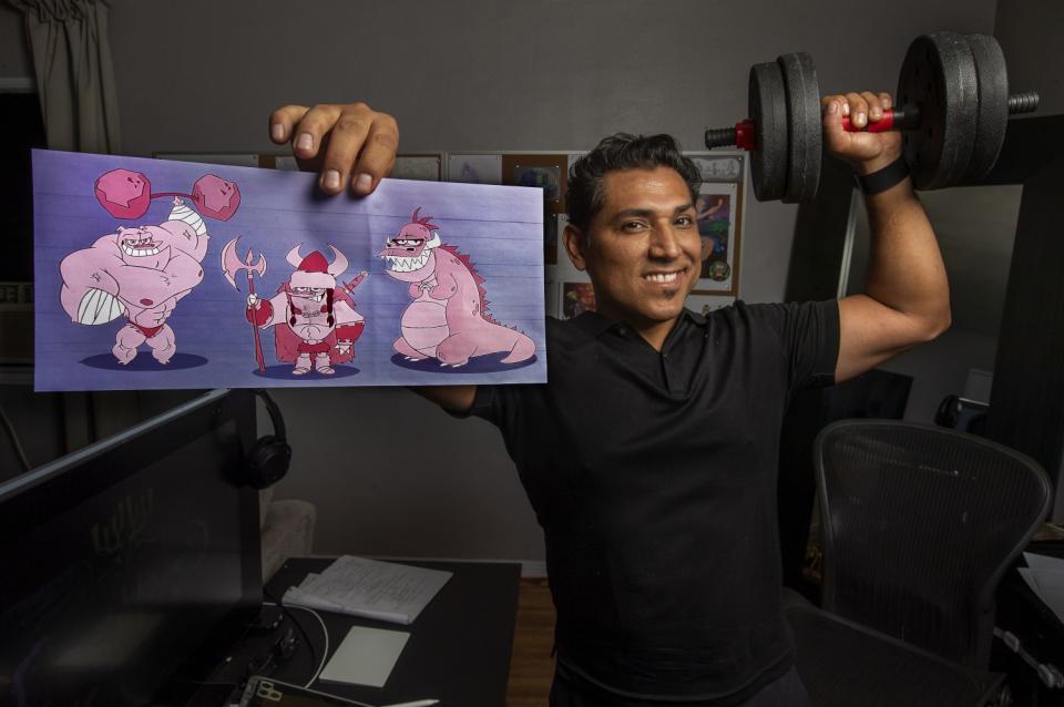 Artist Jose Zelaya holds up a portfolio piece. Zelaya has worked for Disney since 1997.