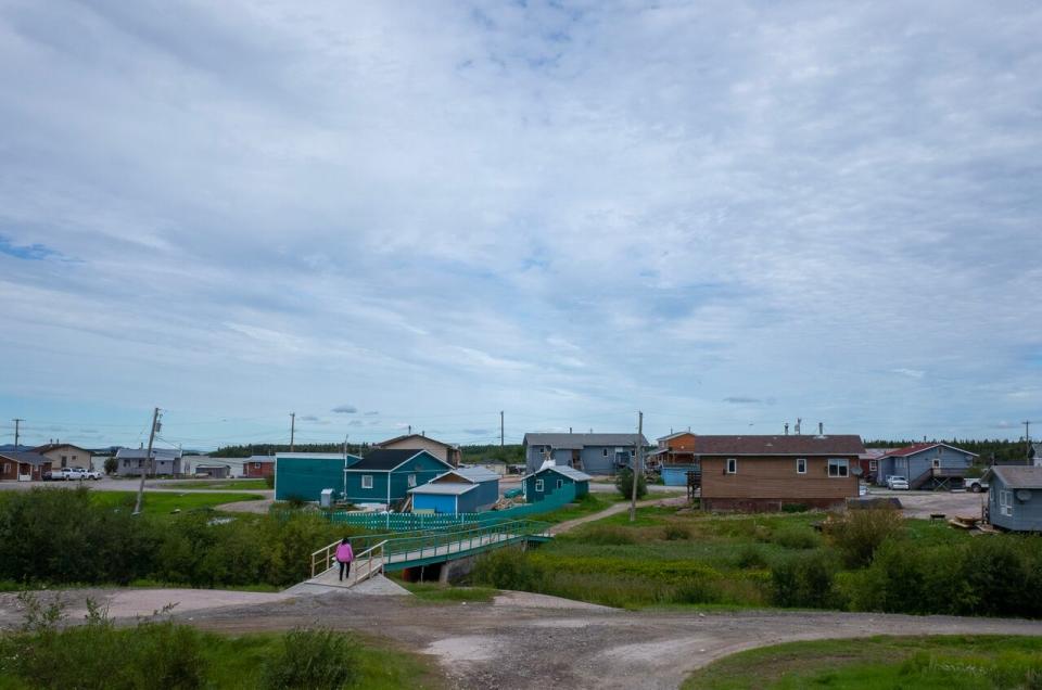 A woman walks across a pedestrian bridge in Behchoko, N.W.T., on Aug. 11, 2020.