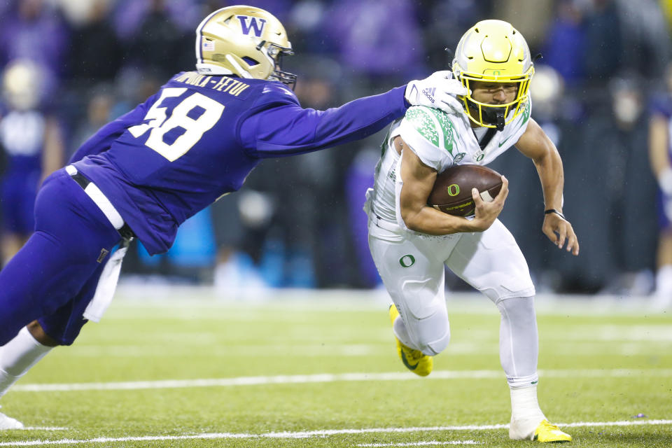 Nov. 6, 2021; Seattle, Washington; Oregon Ducks running back Travis Dye (26) breaks a tackle attempt by Washington Huskies linebacker Zion Tupuola-Fetui (58) during the fourth quarter at Alaska Airlines Field at Husky Stadium. Joe Nicholson-USA TODAY Sports