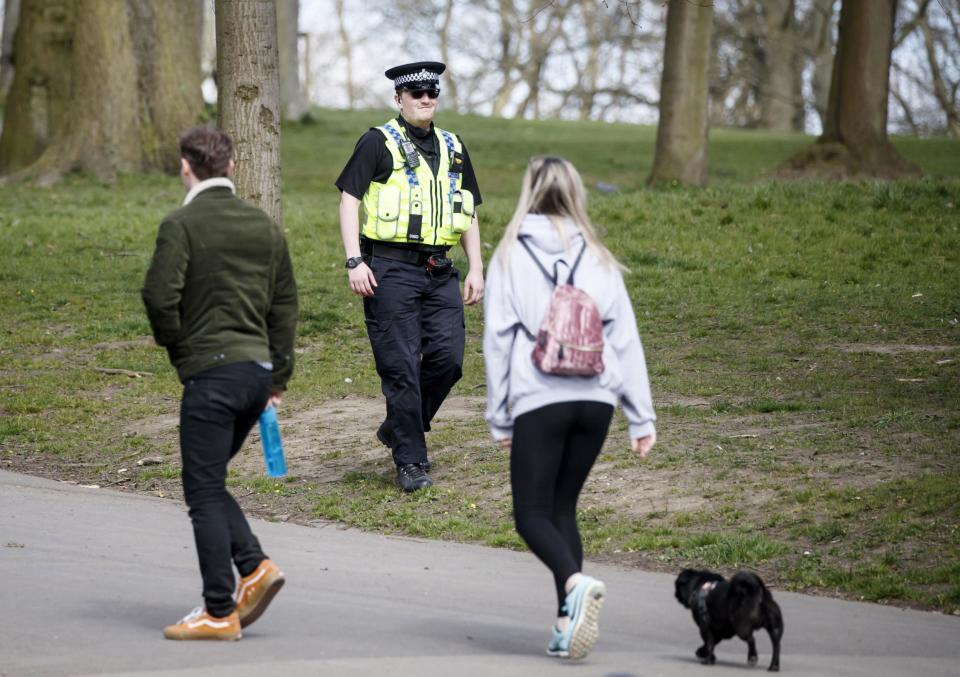 A policeman walks past a people exercising with a dog amid the coronavirus lockdown (PA)