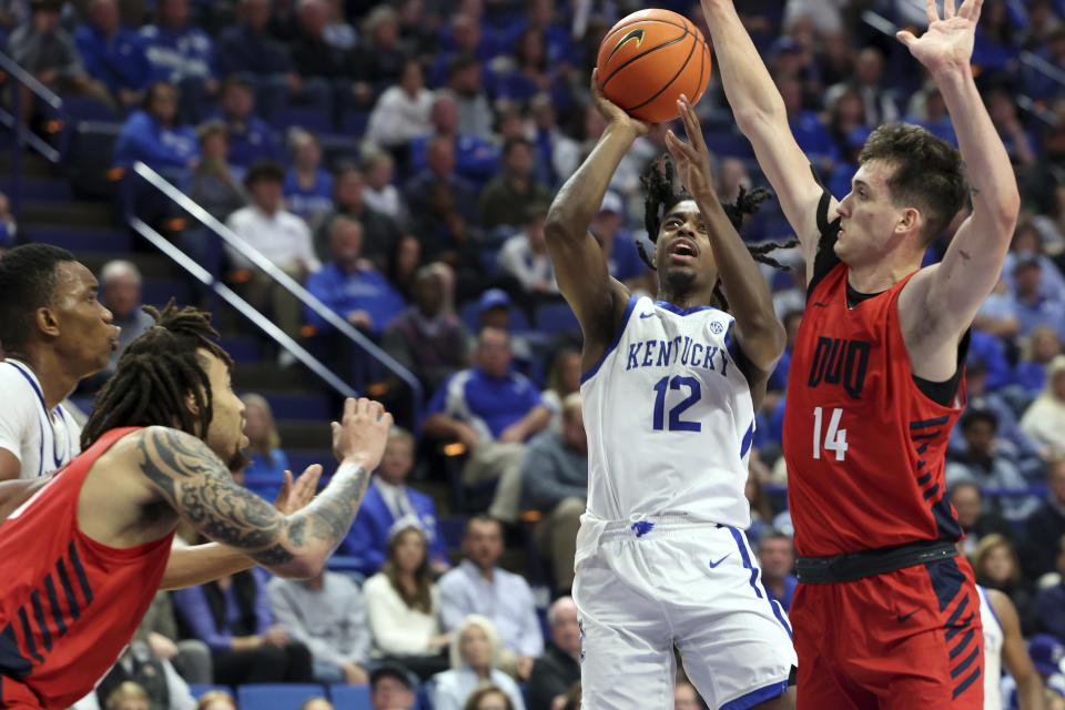 Kentucky's Antonio Reeves (12) shoots between Duquesne's Joe Reece, second from left, and Matus Hronsky (14) during the second half of an NCAA college basketball game in Lexington, Ky., Friday, Nov. 11, 2022. (AP Photo/James Crisp)