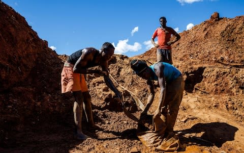 Miners fill bags with ore at Manzou Farm, owned by Grace Mugabe - Credit:  JEKESAI NJIKIZANA/ AFP