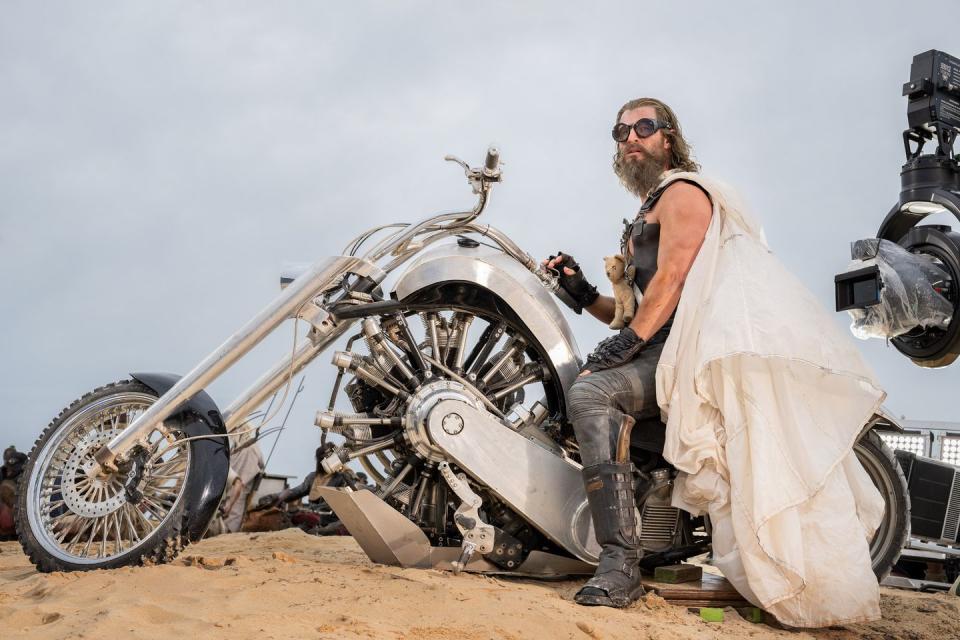 a person in a white suit standing next to a motorcycle