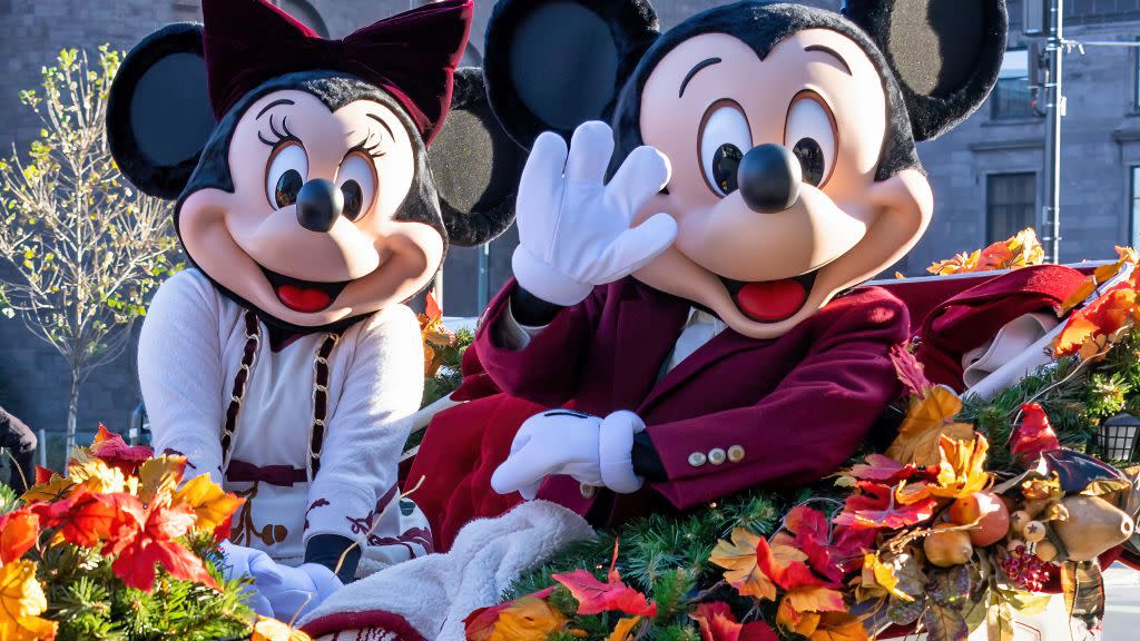 mickey and minnie mouse sitting in carriage decorated with fall leaves mickey is waving