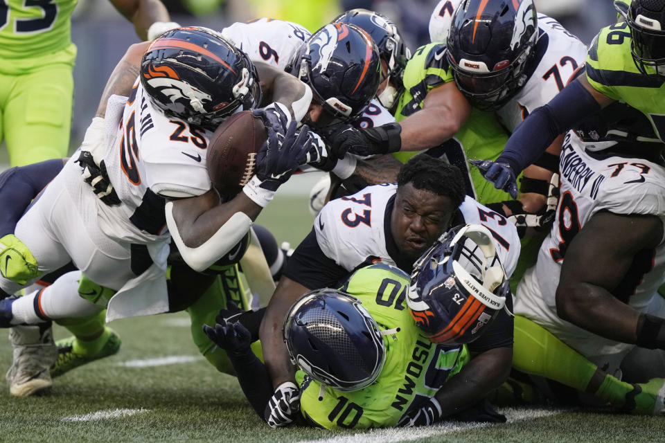 Denver Broncos running back Melvin Gordon III, upper left, fumbles the ball as Broncos offensive tackle Cameron Fleming (73) loses his helmet during the second half of an NFL football game against the Seattle Seahawks, Monday, Sept. 12, 2022, in Seattle. (AP Photo/Stephen Brashear)