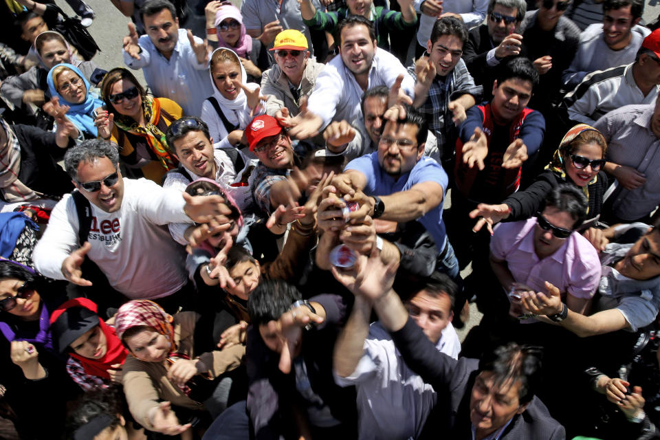 Iranians try to get ice-cream from Choopan dairy workers, unseen, during a ceremony unveiling 5-tons of ice-cream at the Tochal mountainous area of northern Tehran, Iran, Monday, April 1, 2013. Choopan dairy unveiled 5-tons of chocolate ice-cream, the largest in the world, according to the factory officials. (AP Photo/Ebrahim Noroozi)