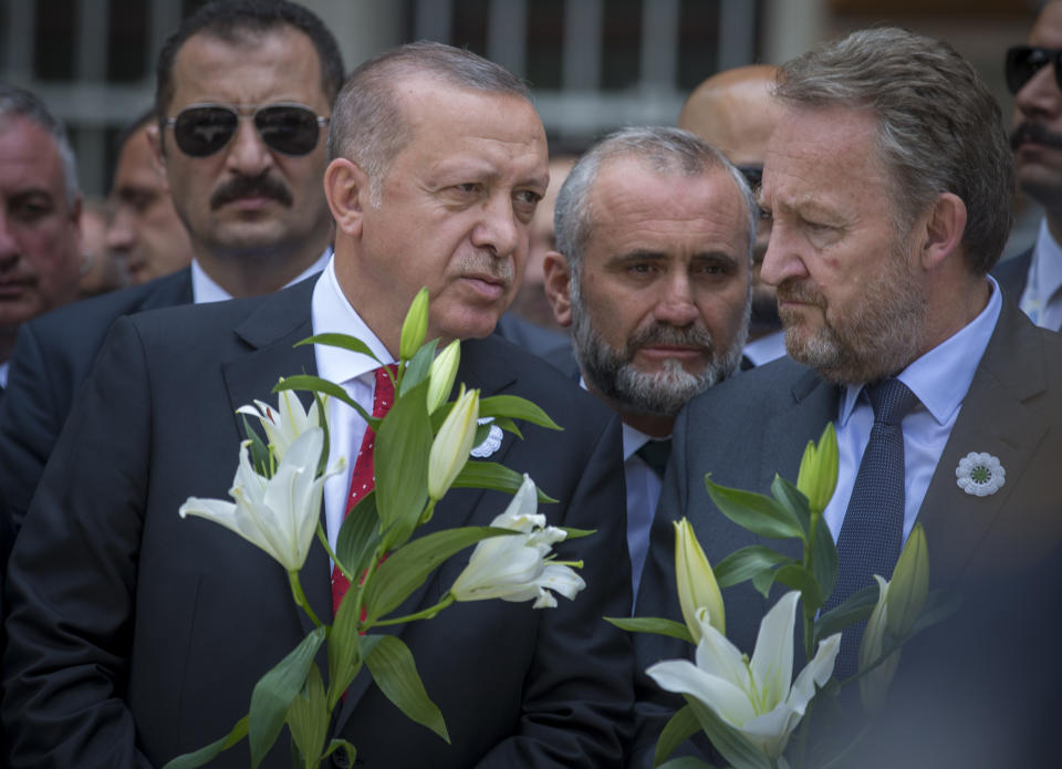 Turkey's president Rejep Tayyip Erdogan, left, and Bakir Izetbegovic, son of former Bosnia's president Alija Izetbegovic, hold flowers as they wait for the vehicle carrying the remains of 33 victims of the Srebrenica massacre, in Sarajevo, Bosnia, Tuesday, July 9, 2019. The remains will be buried in Potocari near Srebrenica, on July 11, 2019, 24 years after Serb troops overran the eastern Bosnian Muslim enclave of Srebrenica and executed some 8,000 Muslim men and boys, which international courts have labeled as an act of genocide. (AP Photo/Darko Bandic)
