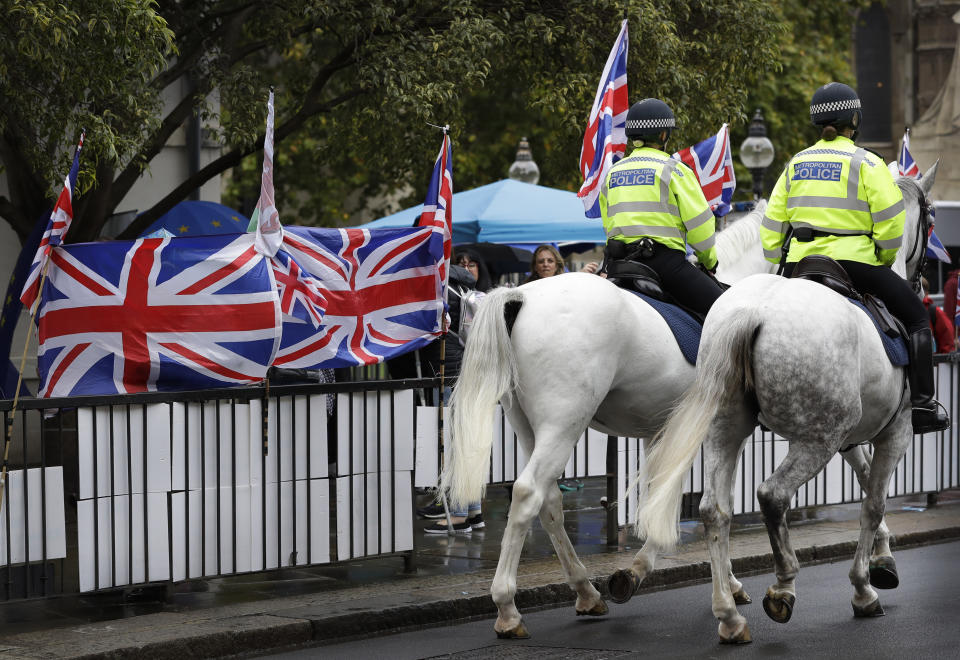 Police horses pass a confusion of flags and banners both pro and against Brexit, outside Parliament in London, Monday, Oct. 21, 2019. The European Commission says the fact that British Prime Minister Boris Johnson did not sign a letter requesting a three-month extension of the Brexit deadline has no impact on whether it is valid and that the European Union is considering the request. (AP Photo/Kirsty Wigglesworth)