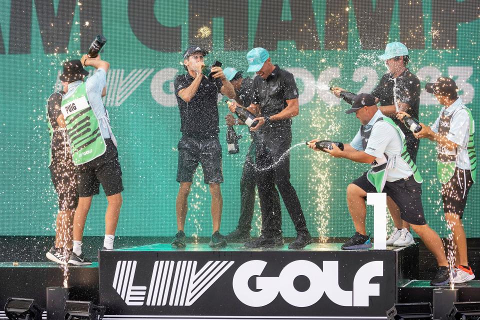 Professional golfers celebrate on stage with the team trophy during LIV Golf DC at the Trump National Golf Club near Washington on May 28, 2023.
