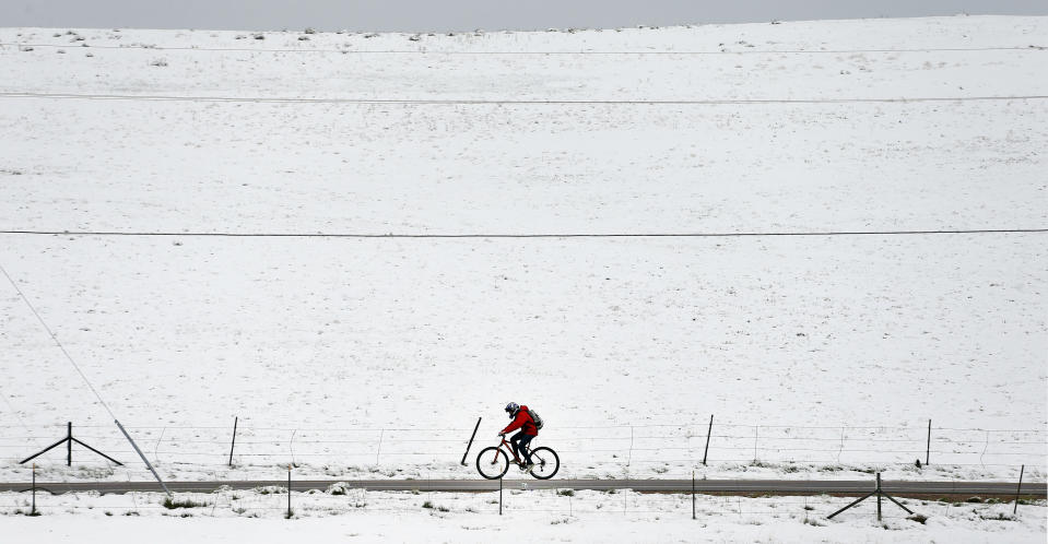 A biker passes fresh snow from the fringe of a major spring snowstorm in the nearby mountains, in Superior, Colo., on Monday, May 12, 2014. A spring storm has brought up to 3 feet of snow to the Rockies and severe thunderstorms and tornadoes to the Midwest. In Colorado, the snow that began falling on Mother's Day caused some power outages as it weighed down newly greening trees. (AP Photo/Brennan Linsley)
