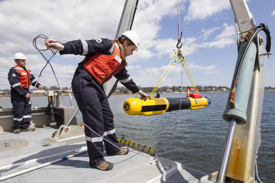 A submarine built by Bluefin Robotics is lowered into the water by systems engineer Cheryl Mierzwa in Quincy, Mass., Wednesday, April 9, 2014. Bluefin Robotics shipped a version of their submarine to help locate the missing Malaysian Airlines Flight 370, by using its side-scan sonar. (AP Photo/Scott Eisen)