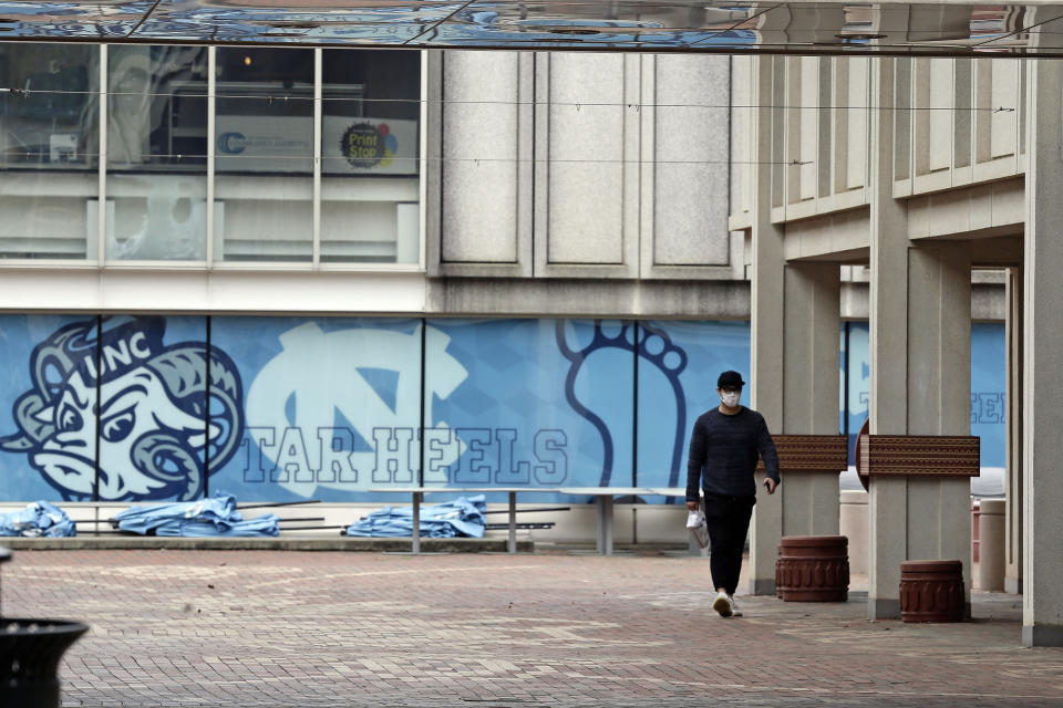 FILE - In this March 18, 2020 file photo, a pedestrian walks through campus at the University of North Carolina in Chapel Hill, N.C. A federal judge has ruled that North Carolina’s flagship public university may continue to consider race as a factor in its undergraduate admissions. The ruling goes against plaintiffs who argued that race-based admissions put white and Asian students at a disadvantage. U.S. District Judge Loretta Biggs ruled late Monday, Oct. 18, 2021 that the University of North Carolina has shown that it has a compelling reason to pursue a diverse student body and has demonstrated that measurable benefits come from that goal. (AP Photo/Gerry Broome, File)