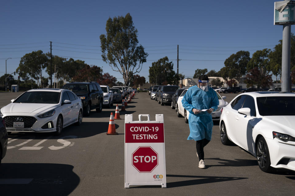 FILE - In this Nov. 16, 2020, file photo, student nurse Ryan Eachus collects forms as cars line up for COVID-19 testing at a testing site set up the OC Fairgrounds in Costa Mesa, Calif. Congress is bracing for President-elect Joe Biden to move beyond the Trump administration’s state-by-state approach to the COVID-19 crisis and build out a national strategy to fight the pandemic and distribute the eventual vaccine. (AP Photo/Jae C. Hong, File)