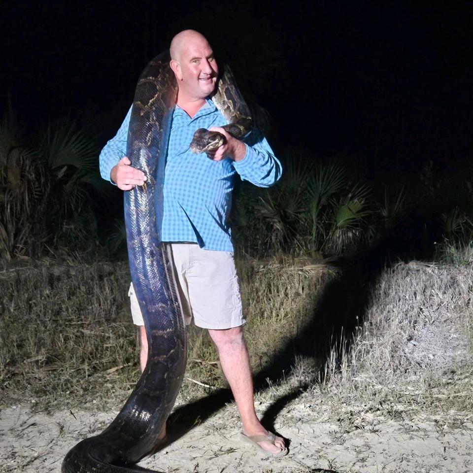Conservationist Mike Elfenbein holds a 198-pound Burmese python, he and a team of python hunters captured in the Big Cypress Preserve on Nov. 3. He was joined by his son, Cole, and Trey Barber, Carter Gavlock and Holden Hunter for the hunt.